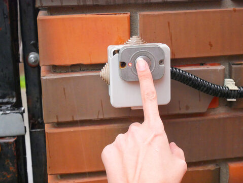 Finger pressing red button on white electrical switch box