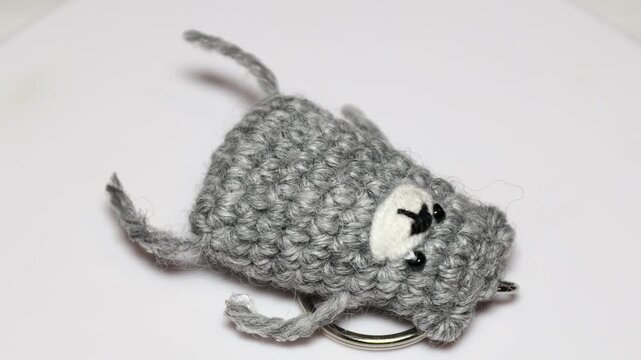 A small, handmade keychain with a stuffed animal attached, suitable for a gift or a personal keepsake. Rotating in a circle