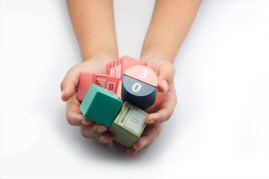 Overhead view of a young girl holding a handful of block toys in front of a white background