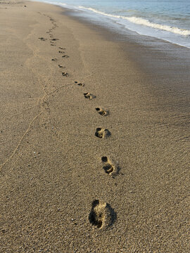 Close-up of footprints on a sandy beach along the shoreline, Indonesia