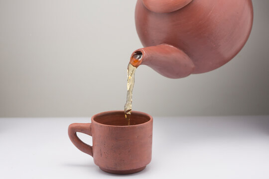 Close-up of green tea being poured into a clay mug from a traditional chinese clay teapot