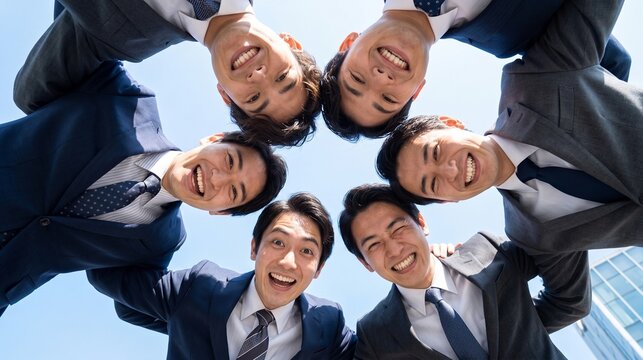 結束力を強めるために円陣を組み笑顔を交わす男性ビジネスマンたち