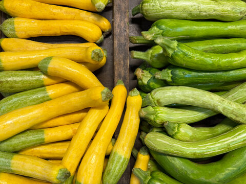 Overhead view of stacks of green and yellow courgettes for sale in a shop