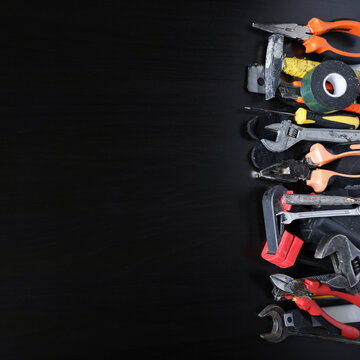 Assorted hand tools arranged along right edge on dark wooden surface, copy space for repair