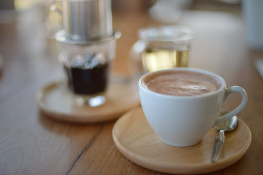 Close-up of a cup of Hot Chocolate on a wooden table with an espresso coffee and herbal tea in the background