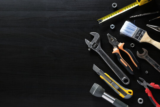 Assorted hand tools arranged on dark wooden surface with large empty copy space