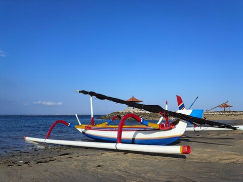 Close-up side view of a Traditional wooden outrigger boat (jukung) on a sandy beach, Bali, Indonesia