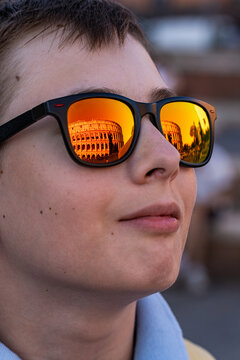 Close-up portrait of a teenage boy wearing sunglasses with the Roman Colosseum reflected in them, Rome, Lazio, Italy