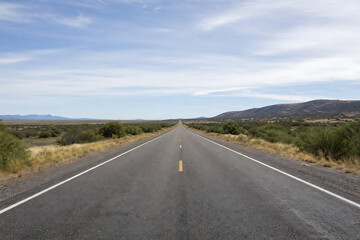 Fototapeta premium Cinematic wide-angle Straight desert highway to horizon under vast sky. Symbolizing journey, freedom, adventure, a path to scenic places like Gandikota