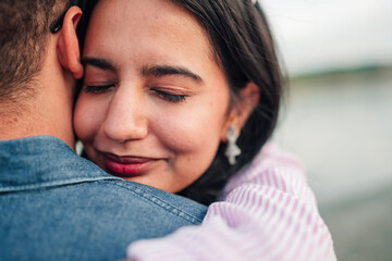 Happy young woman smiling with closed eyes, embracing and feeling tender affection for her partner