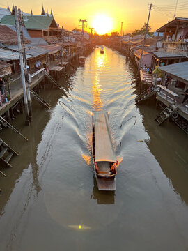 Sunset over a boat sailing along a canal, Amphawa village, Samut Songkhram Province, Thailand