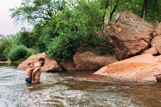 Man Carrying Son on Back Through River
