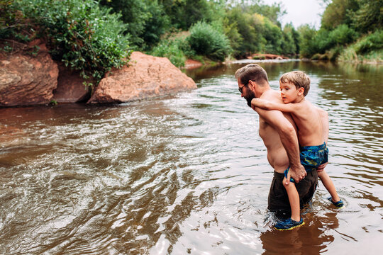 Man Carrying Son on Back Through River