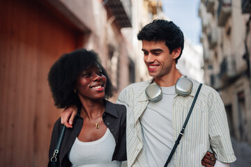 Happy interracial couple enjoying a casual walk through the city smiling, embracing diversity and...