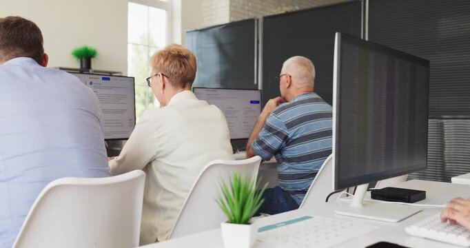 Seniors students in classroom learning computers training. Group of adults at monitors in a bright lab focused on practical education and digital skills. Concept of adult digital learning.