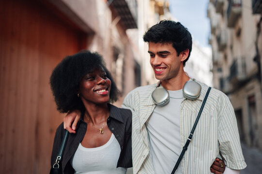 Happy interracial couple enjoying a casual walk through the city smiling, embracing diversity and connection