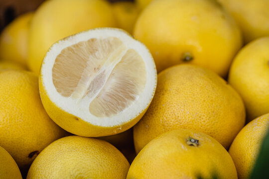 Fresh Pomelo or Sweetie citrus fruit, featuring one fruit cut in half at a fruit and vegetables market