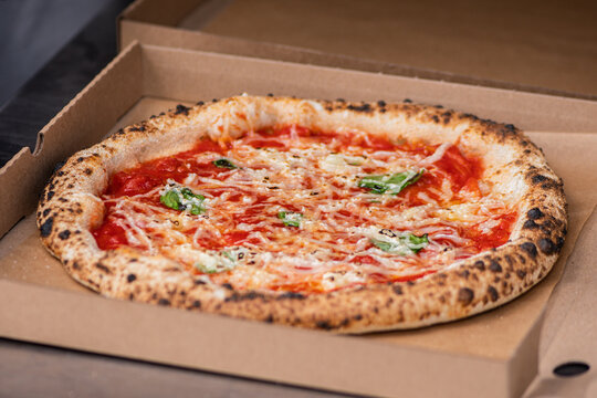 Freshly baked Neapolitan-style Margherita pizza inside a cardboard takeout box