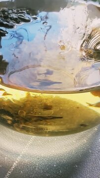 Macro footage of fresh tea leaves blooming in hot water, with gentle steam and fluid movement evoking self-care, relaxation, and a peaceful daily ritual.