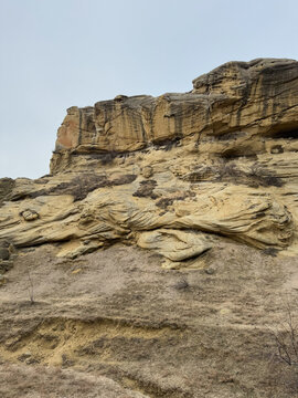 Eroded sandstone rock with layered formations and dry soil foreground.