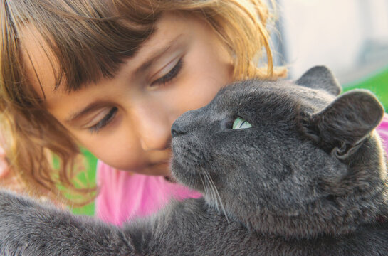 A child loves a cat outdoors. Selective focus.