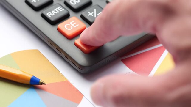 A hand repeatedly pressing the orange ON/C reset button on a black calculator during financial report analysis.