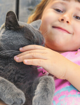 A child loves a cat outdoors. Selective focus.