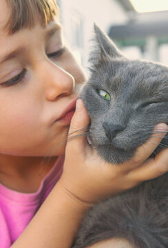 A child loves a cat outdoors. Selective focus.