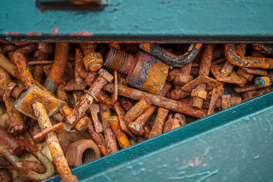 Rusty screws and nuts in a blue steal container.