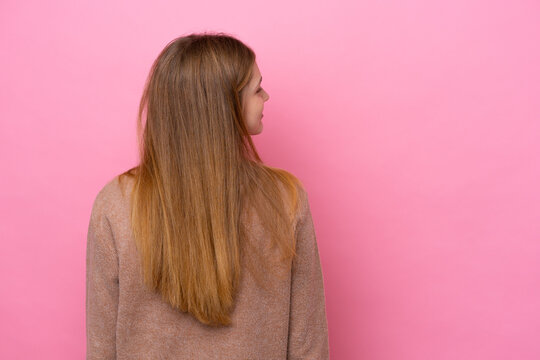 Teenager Russian girl isolated on pink background in back position and looking side