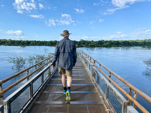 Rear view of a Man walking on the Devil's Throat pathway (Paseo Garganta del Diablo) across Rio Iguazu, Iguazu National Park, Misiones Province, Argentina