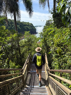 Rear view of a Man walking down the steps on the Lower Circuit with Devil's Throat in the distance, Iguazu Falls, Iguazu National Park, Misiones Province, Argentina