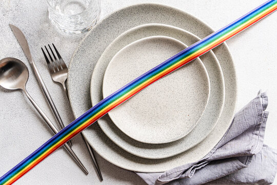 Overhead view of a rainbow ribbon decorating a minimalist place setting  symbolising diversity and inclusion