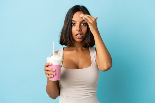 Young woman with strawberry milkshake isolated on blue background has realized something and intending the solution