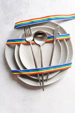 Overhead view of a rainbow ribbon decorating a minimalist place setting  symbolising diversity and inclusion