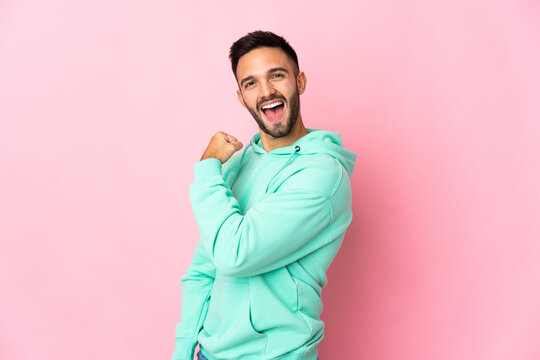 Young caucasian man isolated on pink background celebrating a victory