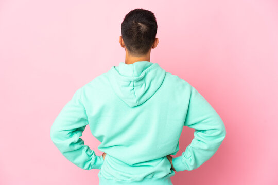 Young caucasian man isolated on pink background in back position