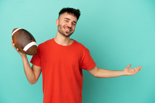 Young Caucasian man playing rugby isolated on blue background extending hands to the side for inviting to come