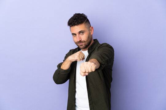 Caucasian man isolated on purple background with fighting gesture