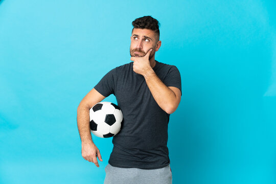 Football player isolated on blue background having doubts and thinking