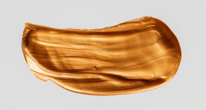 Golden metallic paint brushstroke texture on gray background
