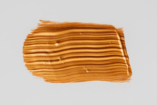 Metallic gold paint brushstroke on white background
