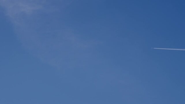 快晴の青空を一直線に横切る飛行機と白く伸びる飛行機雲