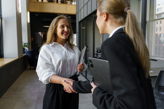 Two professionals in a warm handshake during a meeting in a modern office