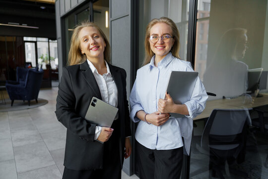 Two professionals smiling in a modern office space showcasing teamwork and confidence in their roles