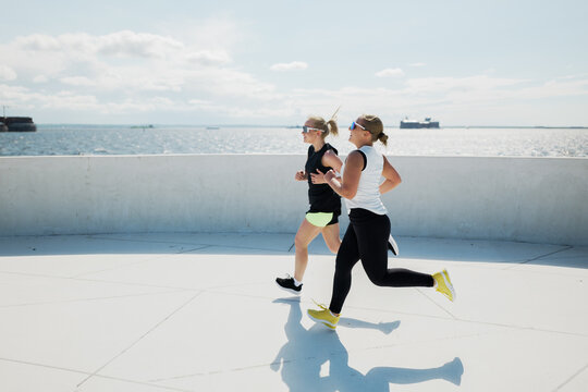 Friends enjoy a sunny afternoon jog by the sparkling waterfront with the ocean breeze invigorating their pace