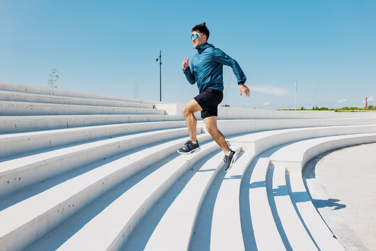 Runner ascends sleek white steps under a bright blue sky, showcasing determination and vigor during morning exercise