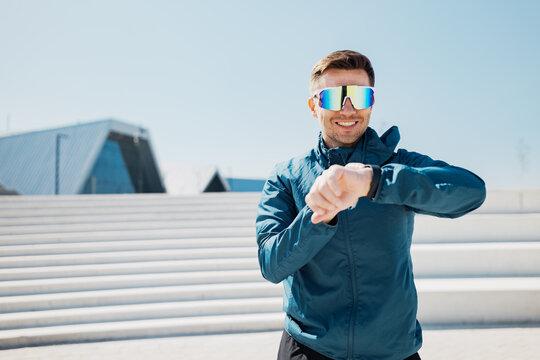 Sporty man checking his smartwatch while enjoying the sunlight in a modern outdoor area