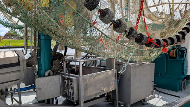 Fishing nets and floats above machinery on a shrimp trawler. 