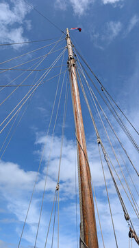 Wooden sailing ship mast and rigging against blue sky. 